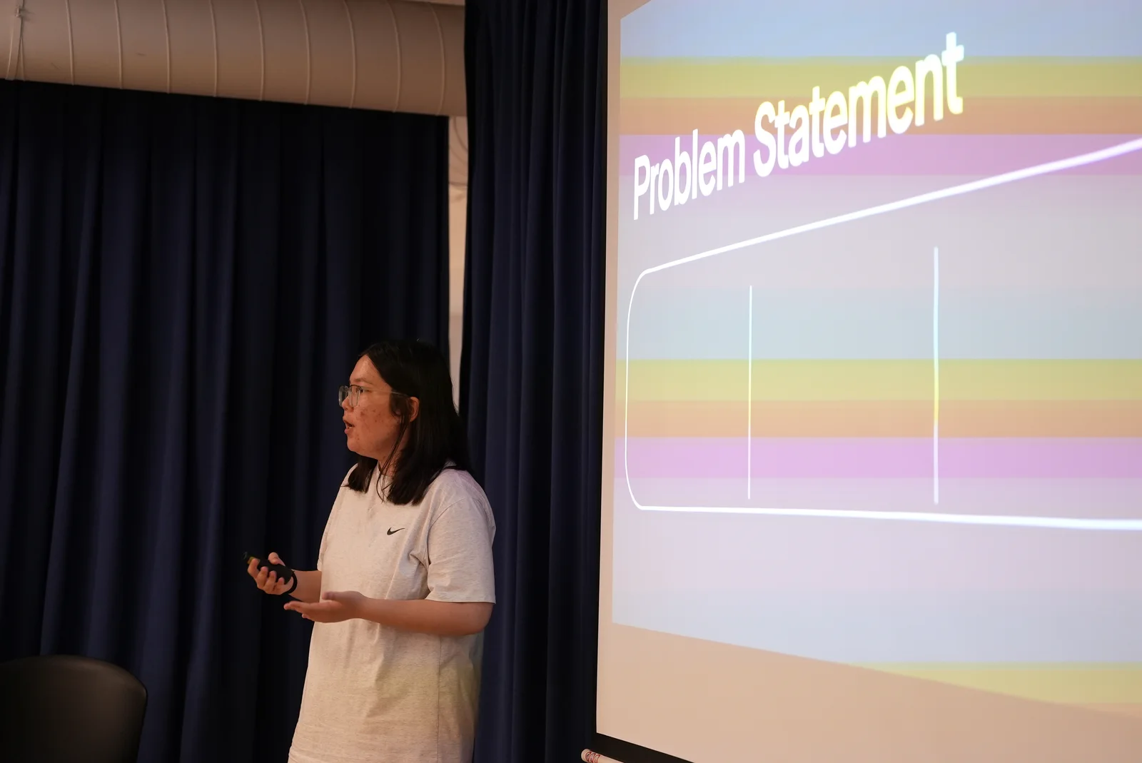 A student presenting a problem statement on stage